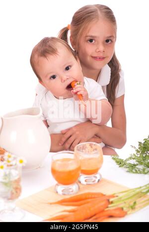 Girl and a little boy, brother and sister and carrot juice isolated on white background Stock Photo