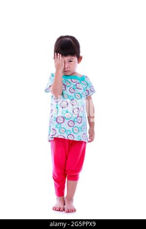 Full length portrait of cute asian girl reviewing eyesight closing eye with hand. Isolated on white background. Studio shoot. Stock Photo