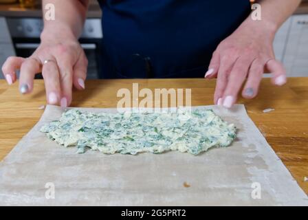 The process of making homemade pies with cottage cheese and dill. The cook puts stuffing in to the dough. Stock Photo
