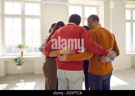 Community of different people huddling standing together in a light modern office Stock Photo
