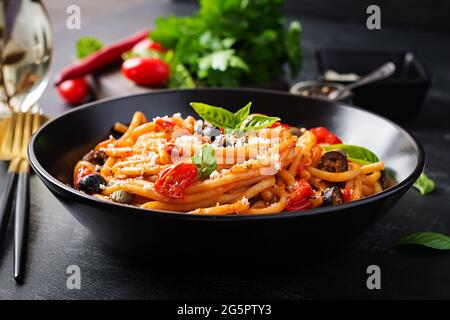 Spaghetti alla puttanesca - italian pasta dish with tomatoes, black olives, capers, anchovies and basil Stock Photo