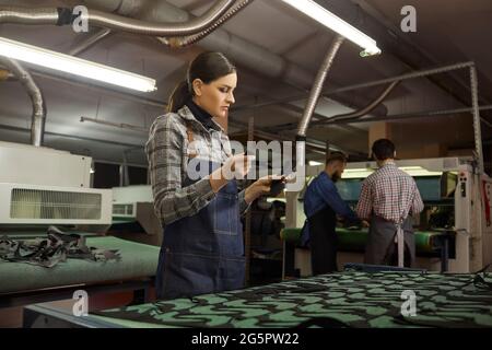 Concentrated young artisan holding leather pieces in shoemaking workshop Stock Photo