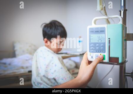 Nurse's hands regulation infusion pump intravenous IV drip on child admitted background. Health care and people concept. Vignette and vintage picture Stock Photo