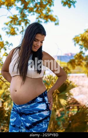 Outdoor photo of a young pregnant woman with long hair Stock Photo
