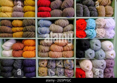 Multicolored woolen knitting threads on folded on shelves close-up. Knitting hobby, handicraft Stock Photo