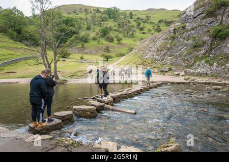 Couple standing on the stepping stones, River Dove having their photo taken. Stock Photo