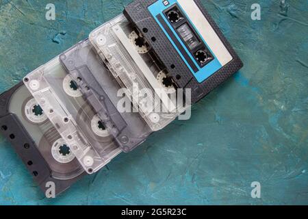 Several audio cassettes lie on top of each other on a dark blue concrete background. Top view Stock Photo