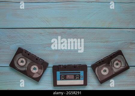 On a blue wooden background at the bottom of the frame are three audio cassettes. There is a place for the text on the top Stock Photo