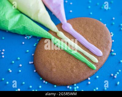 Gingerbread and colored icing for cookie decorating on blue background with sprinkles, close up Stock Photo