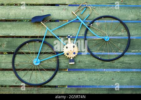Decorative vintage blue bicycle hanging on the wooden planks of a fence. Stock Photo