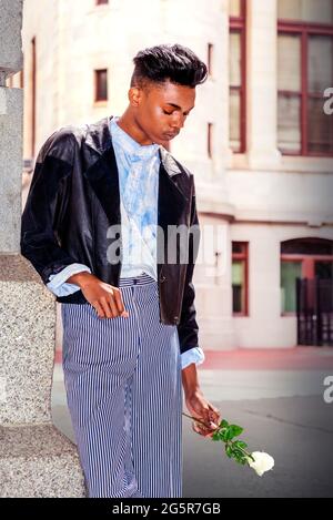 Lonely boy. A 18 years old student, wearing a fashionable black jacket, striped  pants, a blue-dyed white shirt, is standing by the gate on campus, hol  Stock Photo - Alamy