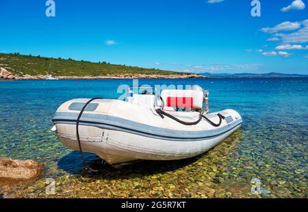 Inflatable rubber motorboat at the shore with beautiful holiday landscape of sea, sun and beach. Stock Photo