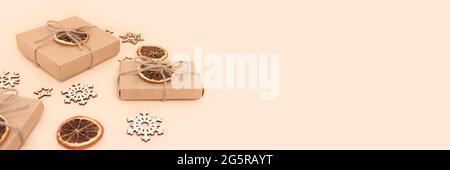Banner with wrapped gift boxes tied with twine rope and New Years toys on a beige background. Holidays concept with place for your design. Stock Photo