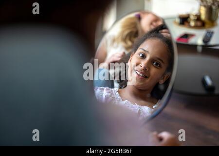 Mother styling daughter's hair at home Stock Photo