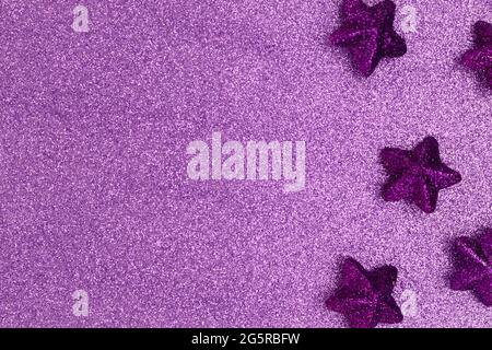 Monochrome composition with glittering stars on a violet textured background with copy space. Stock Photo