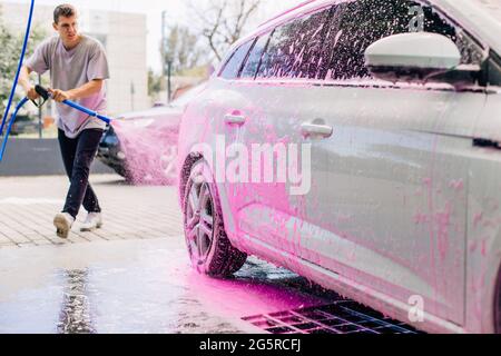 Car wash with foam in car wash station. Carwash. Washing machine at the  station. Car washing concept. Car in foam Stock Photo - Alamy