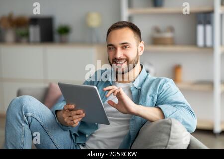 Online life concept. Happy young man using tablet computer, working or studying from home Stock Photo