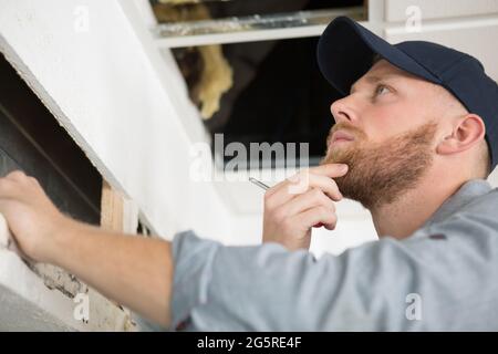 a repairman repairing ceiling air conditioning unit Stock Photo