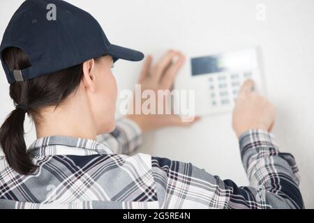 young electrician installing security alarm on wall Stock Photo