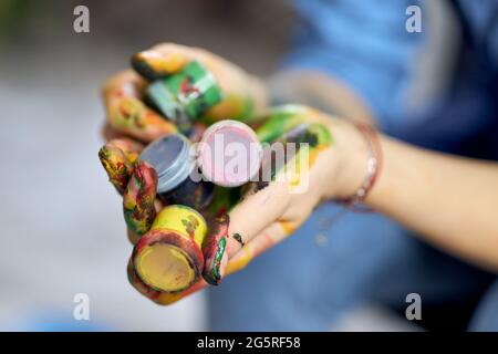 Close up shot of female hands holding colorful acrylic oil paints in jars Stock Photo