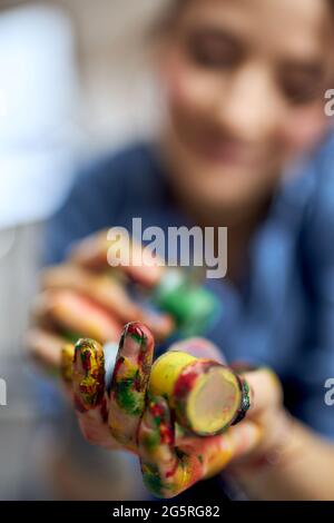 Close up shot of female artist holding colorful acrylic oil paints in jars Stock Photo