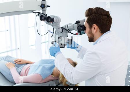 Male dentist using modern equipment for treating in dental clinic Stock Photo