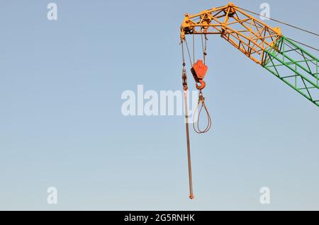 Yellow lifting telescopic arms with hook mobile crane on a background of blue sky. Construction concept - Image Stock Photo