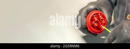High voltage plug. An electrician wearing protective gloves connects the 380 V high-voltage plug. panoramic photo Stock Photo
