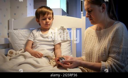 Little sick boy suffering from virus measuring blood oxygen level with pulse oxymeter. Concept of child virus and kids protection during coronavirus Stock Photo