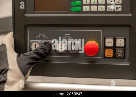 Press Machine Operational Button Hand presses the power button of a woodworking machine at a factory ...