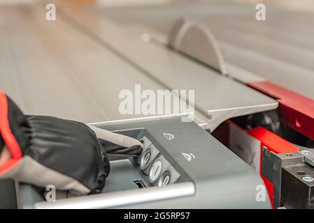 Hand presses the button turning on an industrial machine. Cutting saw blade. Switches for controlling industrial machines and plant equipment in Stock Photo