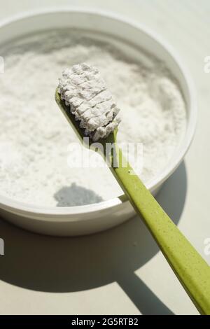 Lime green plastic toothbrush with tooth powder on beige table. Stock Photo