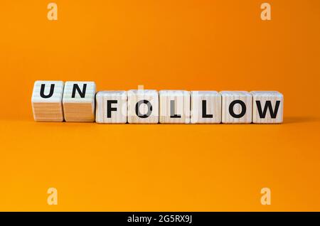 Follow or unfollow symbol. Turned wooden cubes and changed words follow to unfollow. Beautiful orange background, copy space. Business and follow or u Stock Photo