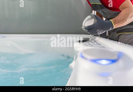 Caucasian SPA Technician Checking on Jacuzzi Filter Close Up Photo. Hot Tub Maintenance. Stock Photo