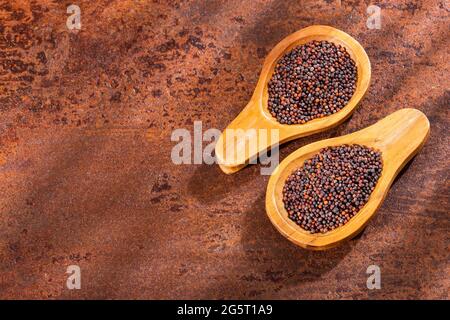 Brown mustard seeds in two wooden spoons Stock Photo