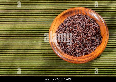 Dark brown mustard seeds in the wooden bowl Stock Photo