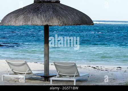sun loungers, beach umbrella on a white sand beach at a hotel resort in Mauritius facing a blue ocean concept tropical island holiday Stock Photo