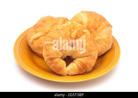 Three Freshly Baked French Croissants on a Yellow Plate Stock Photo