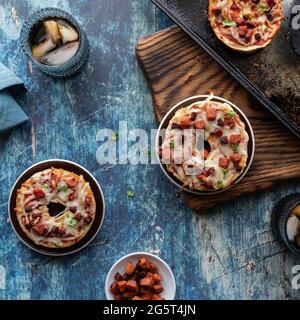 Top down view of pizza bagels on small white rimmed plates against a dark background. Stock Photo