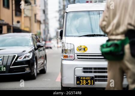 Kyoto, Japan - April 17, 2019: Downtown district area with Yamato company delivery truck van with cat logo closeup driving on street road in urban Stock Photo