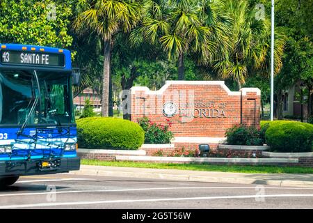 Gainesville, USA - April 27, 2018: Sign for entrance to campus of UF University of Florida in central state with bus on street road Stock Photo