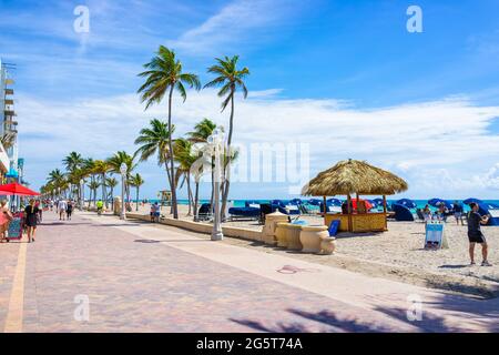 Hollywood, USA - May 6, 2018: Beach boardwalk broadwalk in Florida Miami with sunny day and people walking on promenade by restaurants and palm trees Stock Photo