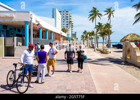 Hollywood, USA - May 6, 2018: Beach broadwalk in Miami Florida with sunny day and people with byccles walking on promenade by restaurants and palm tre Stock Photo