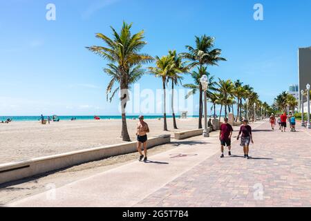 Hollywood, USA - May 6, 2018: Beach broadwalk path walkway in Florida at sunny day and candid people walking jogging running on promenade Stock Photo