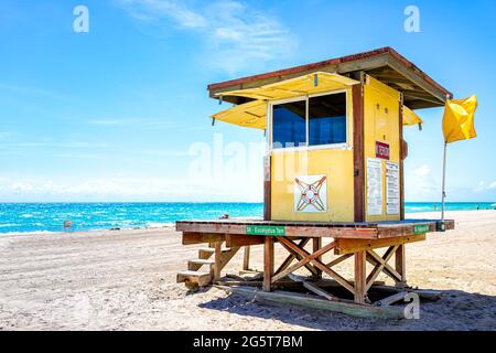 Hollywood, USA - May 6, 2018: Lifeguard building hut along ocean coast in Miami Florida during day with people on sand and turquoise water Stock Photo