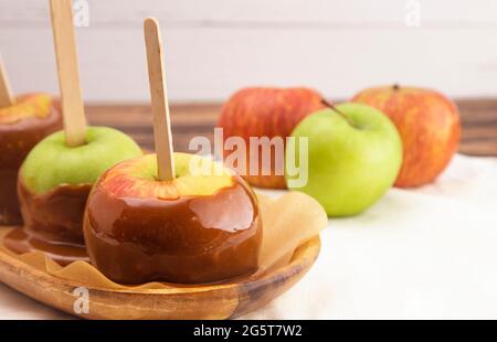 Row of Three Hand Dipped Homemade Caramel Apples on a White Tablecloth Stock Photo