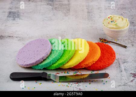 Technique of cake assembly. Frosting and rainbow sponge cake. Stock Photo