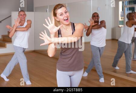 Cheerful woman practicing vigorous movements in group dance class Stock Photo