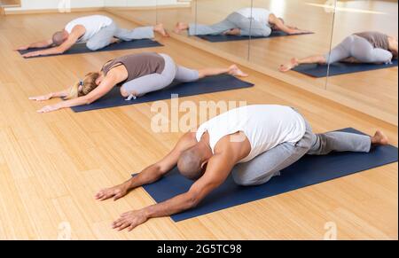 Woman and men stretching during group yoga training Stock Photo