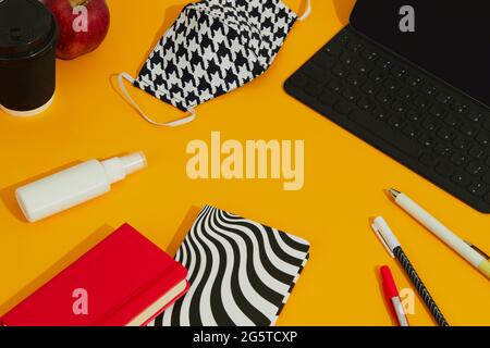 Stationery Keyboard Mask and Hand Sanitizer Against Orange Table. Stock Photo